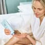 Mujer aplicando la crema corporal en las piernas