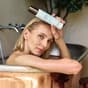 Mujer en la bañera con el limpiador facial en la mano